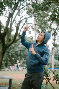 Portrait of young woman standing against trees