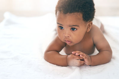 Portrait of cute baby boy lying on bed at home