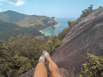 Low section of person on mountain against sky