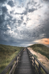View of wooden boardwalk on land against sky
