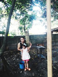 Full length portrait of girl standing against trees