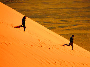 Full length of men walking on land during sunset