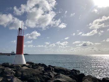 Lighthouse by sea against sky