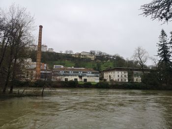 View of buildings by river against sky