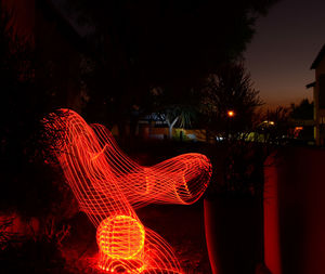 Illuminated light trails against trees at night