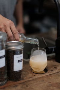 Close-up of hand pouring drink in glass jar on table