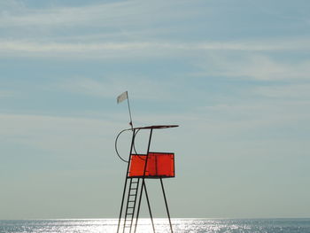 Red flag by sea against sky