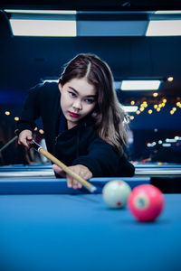 Portrait of young woman playing pool