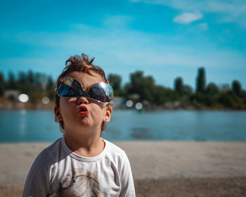 Portrait of young girl wearing sunglasses against lake