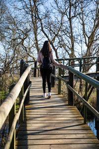 Beautiful woman hiking on a wooden runway above a swamp back shot person