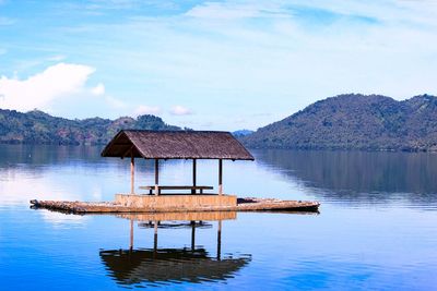 View of hut on wooden raft in lake against sky