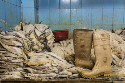 Rubber boots by ice on stacked fish at table