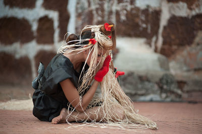 Woman with plants dancing on footpath