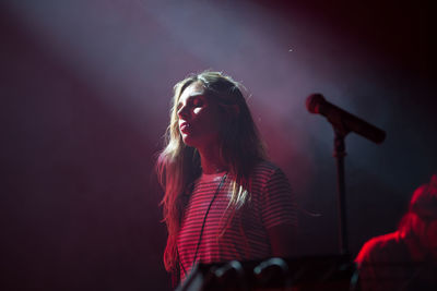 Midsection of woman with arms raised standing in background