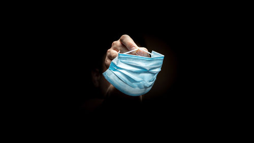 Close-up of hand holding paper over black background