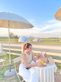 Side view of woman with umbrella on field