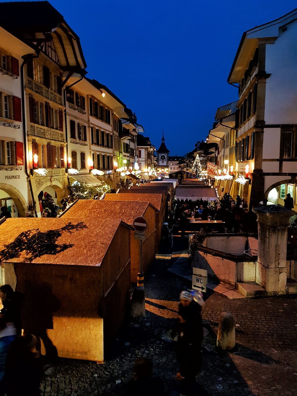 ILLUMINATED STREET AMIDST BUILDINGS AGAINST SKY AT NIGHT