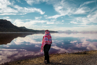 Rear view of woman standing on mountain against sky