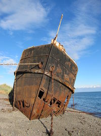 Old rusty ship on beach against sky