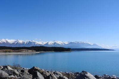 Scenic view of lake by snowcapped mountains against sky