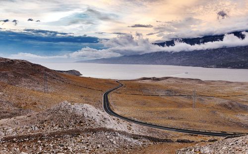 Empty road on barren landscape, sky, clouds, sea.