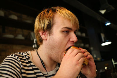 Young man eating burger at restaurant