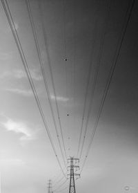 Low angle view of overhead cable cars against sky