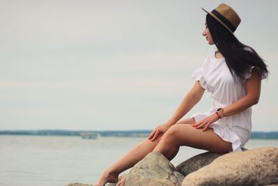 Woman sitting at beach against sky