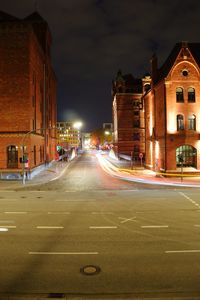 Light trails on road amidst buildings in city at night