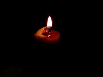 Close-up of illuminated candle in darkroom