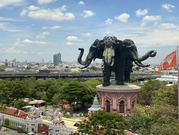 Statue in city against cloudy sky