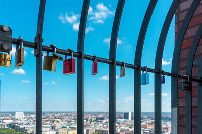 Low angle view of padlocks hanging on railing against sky