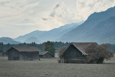 House on field by mountains against sky