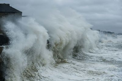 Waves splashing on shore against sky