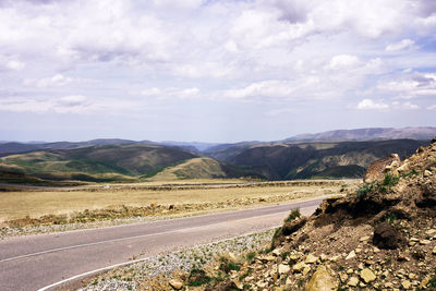 Road leading towards mountains against sky