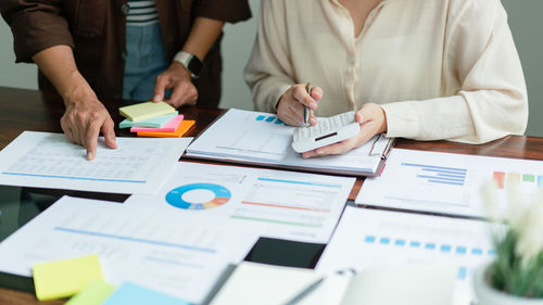 Midsection of business people working on table