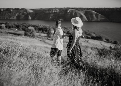 Couple holding hands walking on grassy field