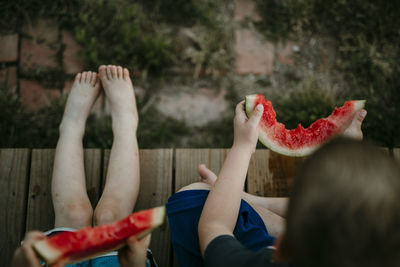 Overhead view of brothers eating watermelon while sitting at porch