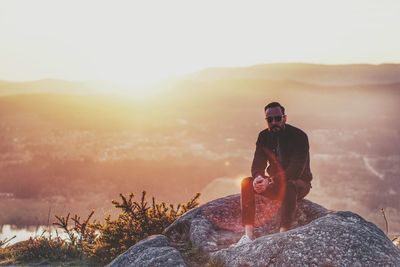 Man sitting on mountain at sunset
