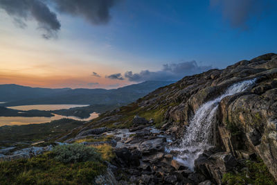 Scenic view of waterfall against sky during sunset