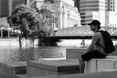 Young woman sitting by water in city