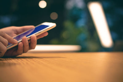 Midsection of man using smart phone on table