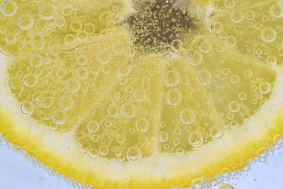 Slice of ripe lemon in water. close-up of lemon in liquid with bubbles. slice of ripe citron in