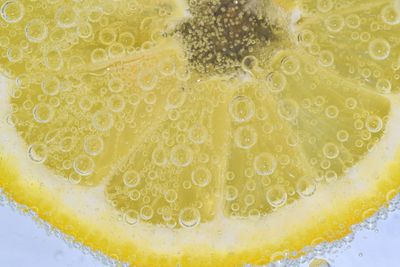 Slice of ripe lemon in water. close-up of lemon in liquid with bubbles. slice of ripe citron in