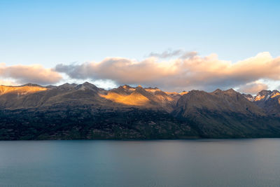 Scenic view of lake by mountains against sky during sunset