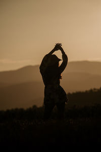 Silhouette woman standing on field against sky during sunset