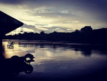 Silhouette man by lake against sky during sunset