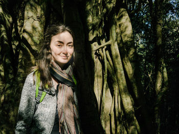 Portrait of smiling young woman standing in forest