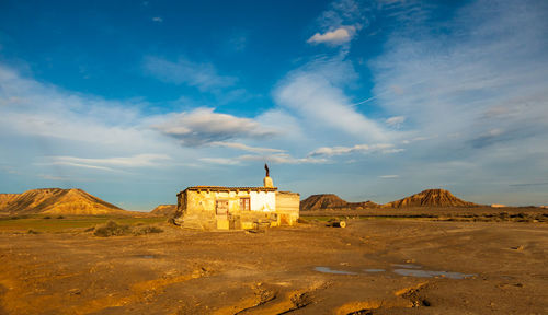 View of old building on land against cloudy sky