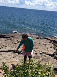 Full length of man on rock at beach against sky